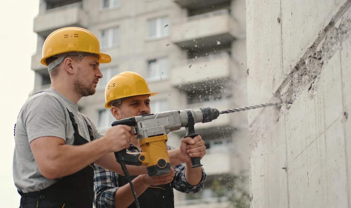 Ouvriers casques jaunes perçant mur immeuble collectif