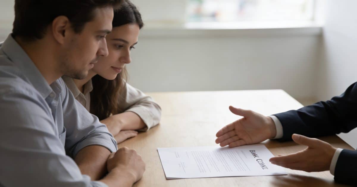 couple assis devant conseiller bancaire regardant contrat
