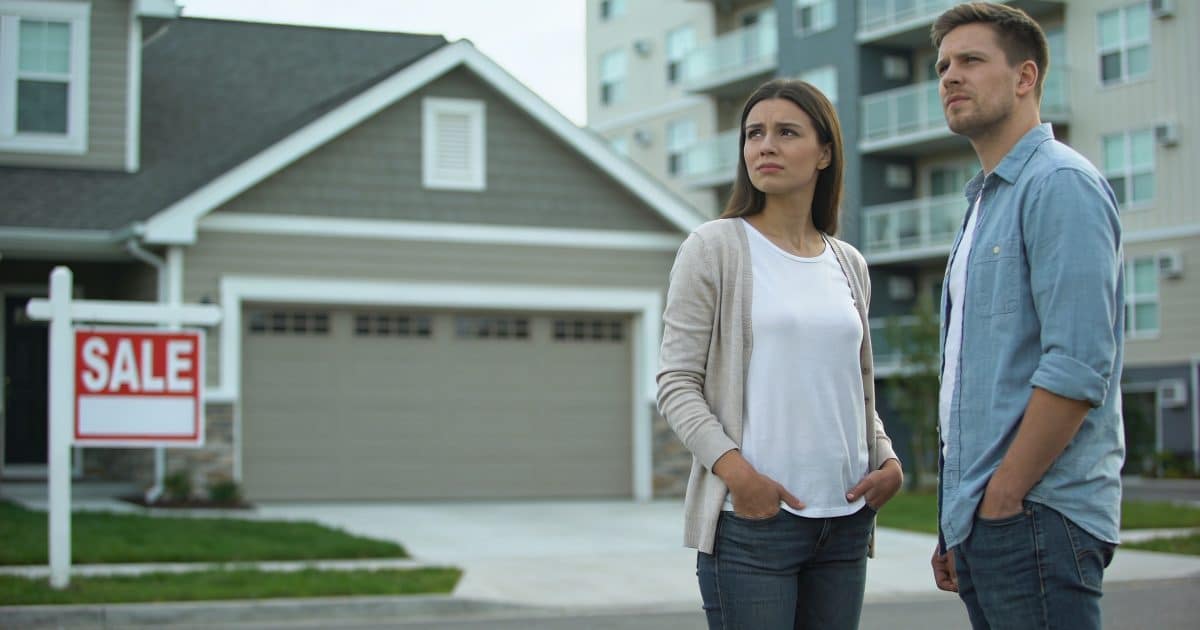 couple hesitant devant maison a vendre et immeuble