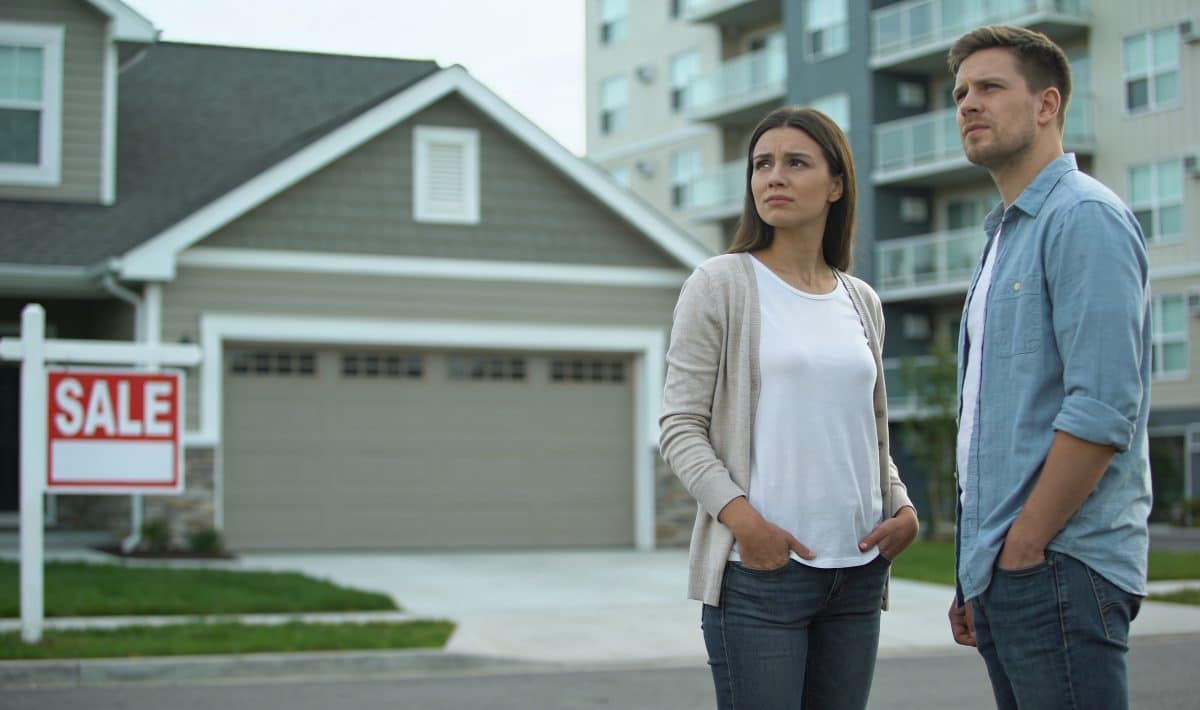 couple hesitant devant maison a vendre et immeuble