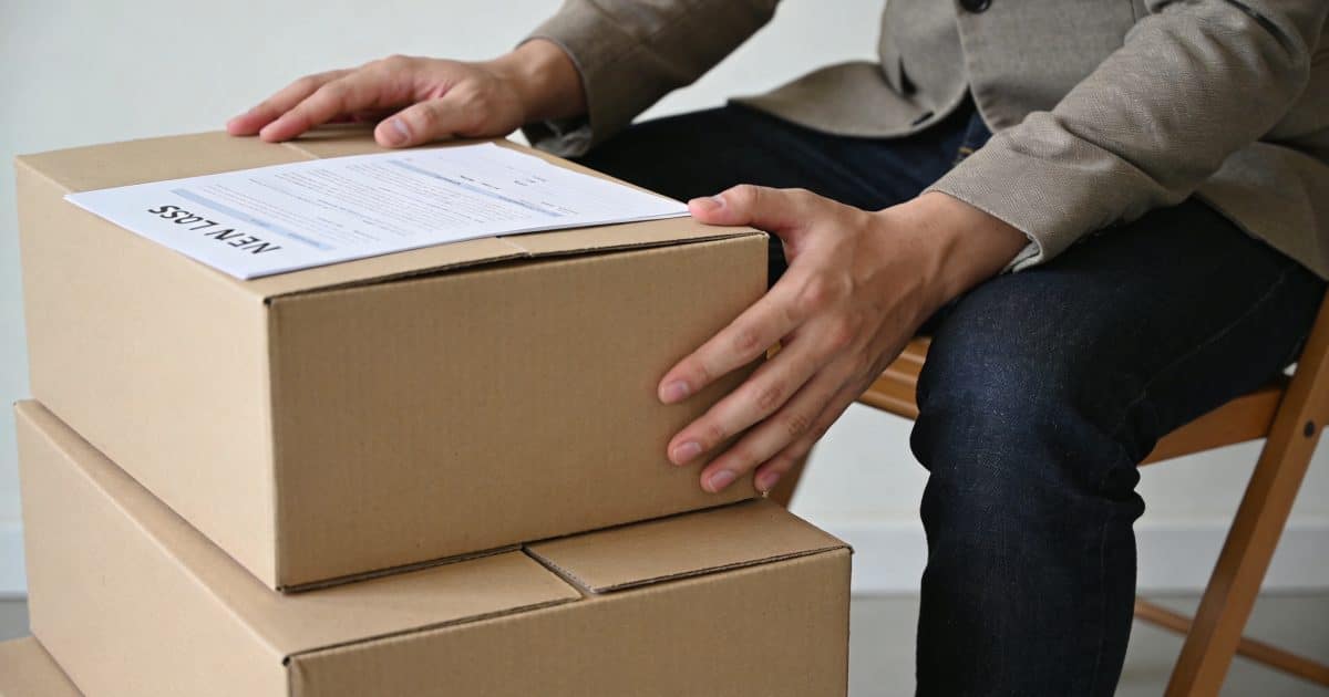 Locataire assis devant cartons de demenagement et nouveau bail