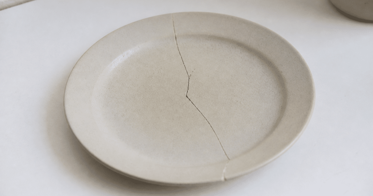 Assiette ceramique fissurée posée sur surface blanche