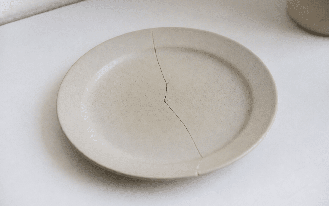 Assiette ceramique fissurée posée sur surface blanche