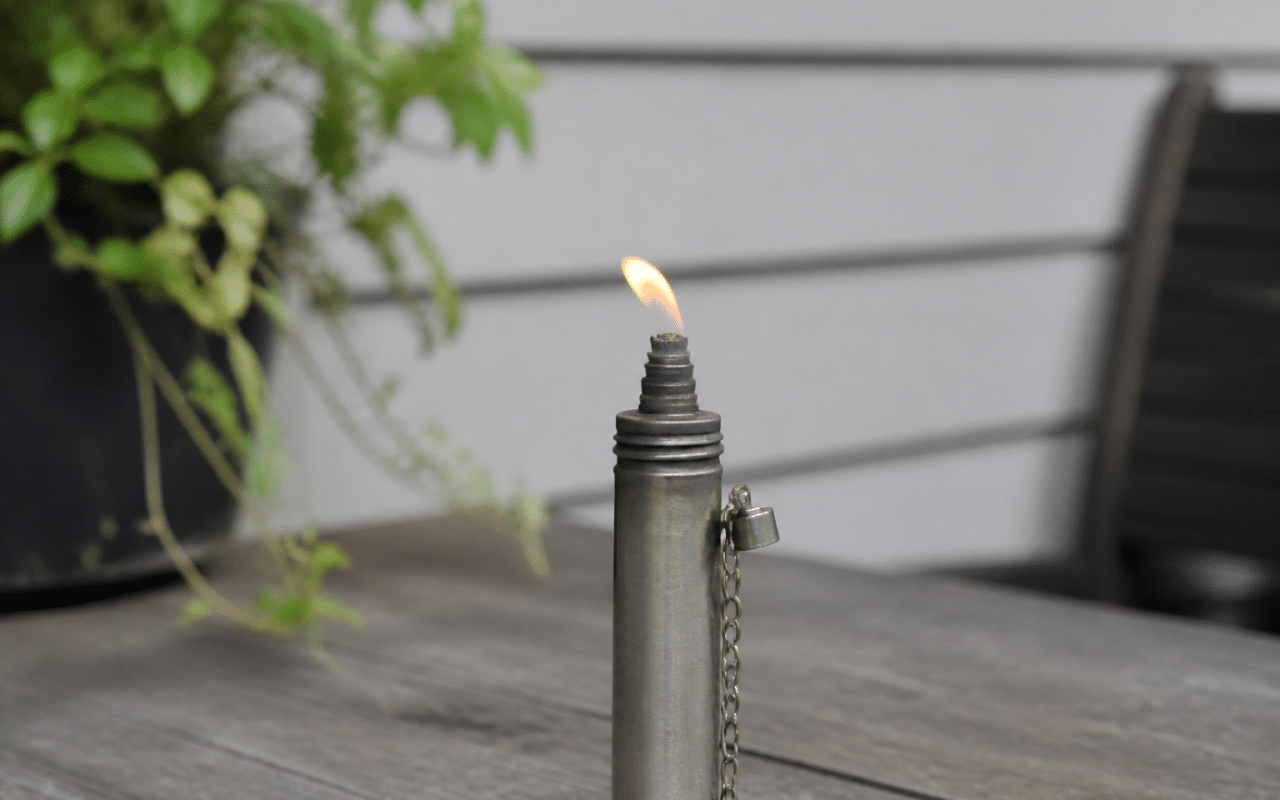 Petit cylindre metallique vertical avec flamme orange faible sortant du bec