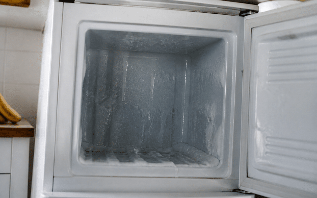 congélateur ouvert avec glaçons fondant sur les parois intérieures