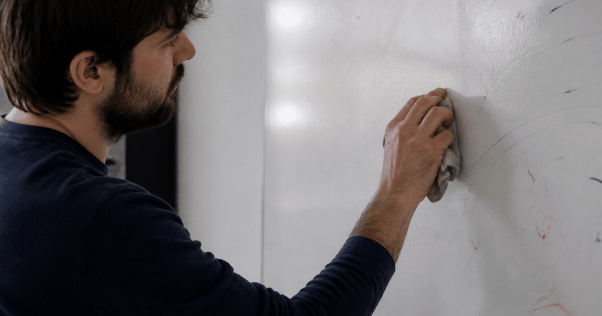 Personne effacant marqueurs colorés sur surface blanche verticale