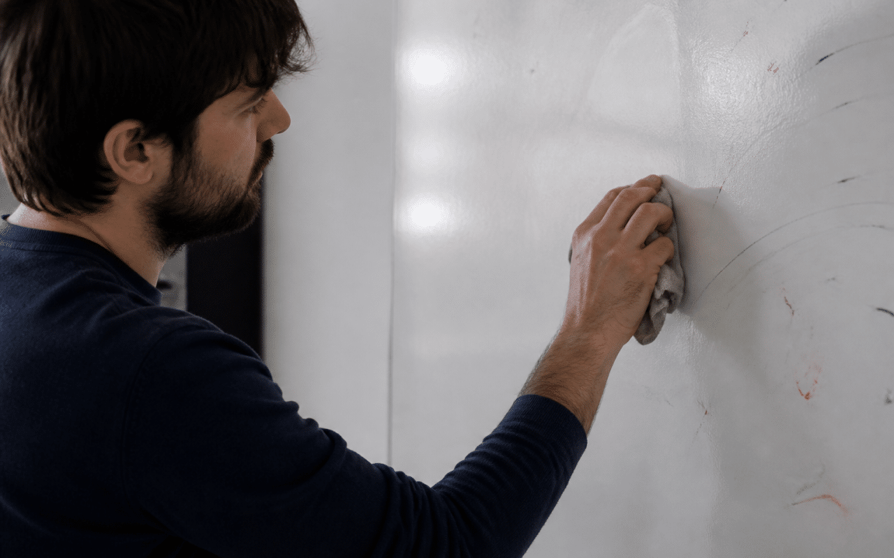 Personne effacant marqueurs colorés sur surface blanche verticale