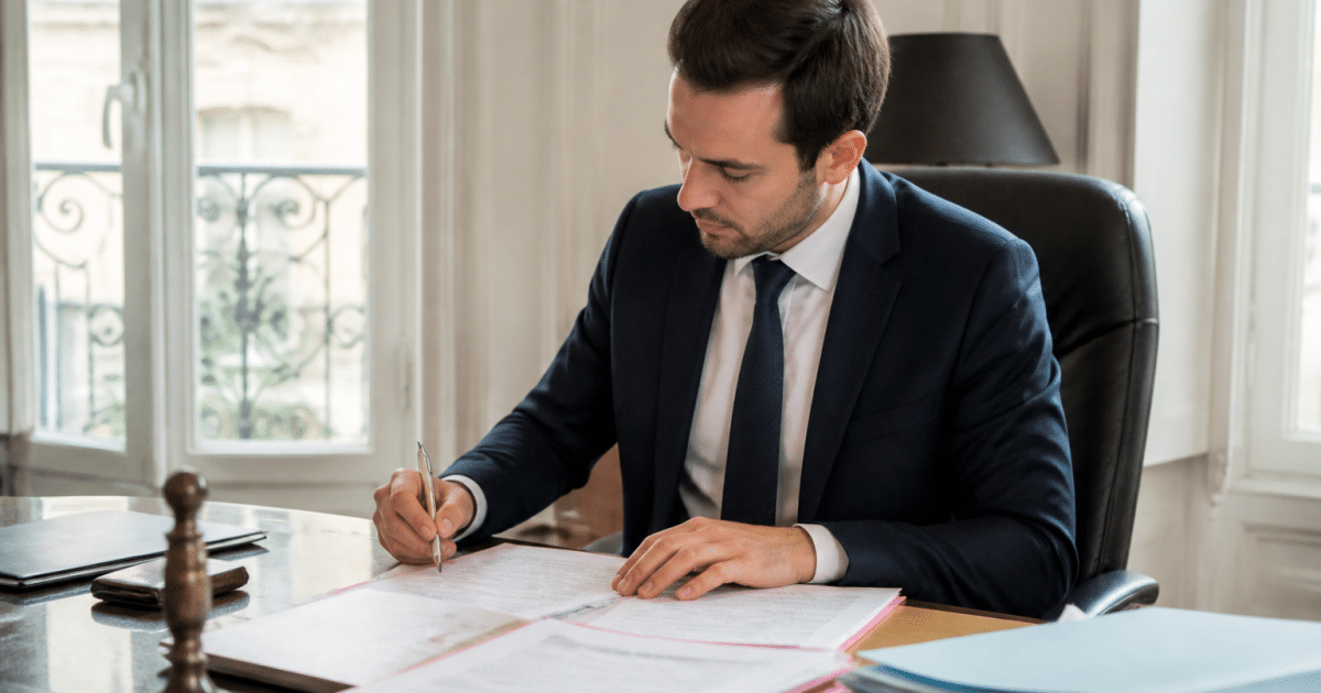 Homme en costume assis a bureau notaire documents