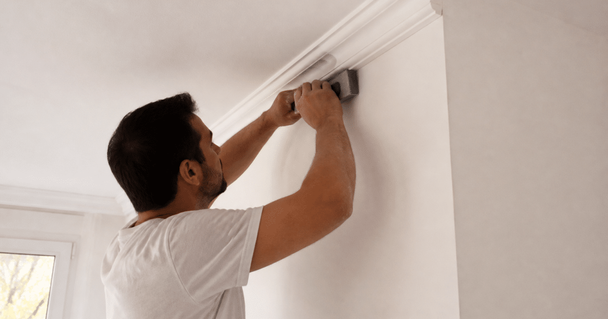 Mains installant moulure decorative blanche au plafond avec outil