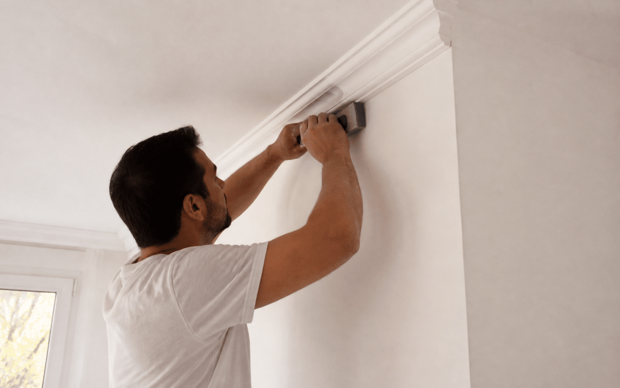 Mains installant moulure decorative blanche au plafond avec outil