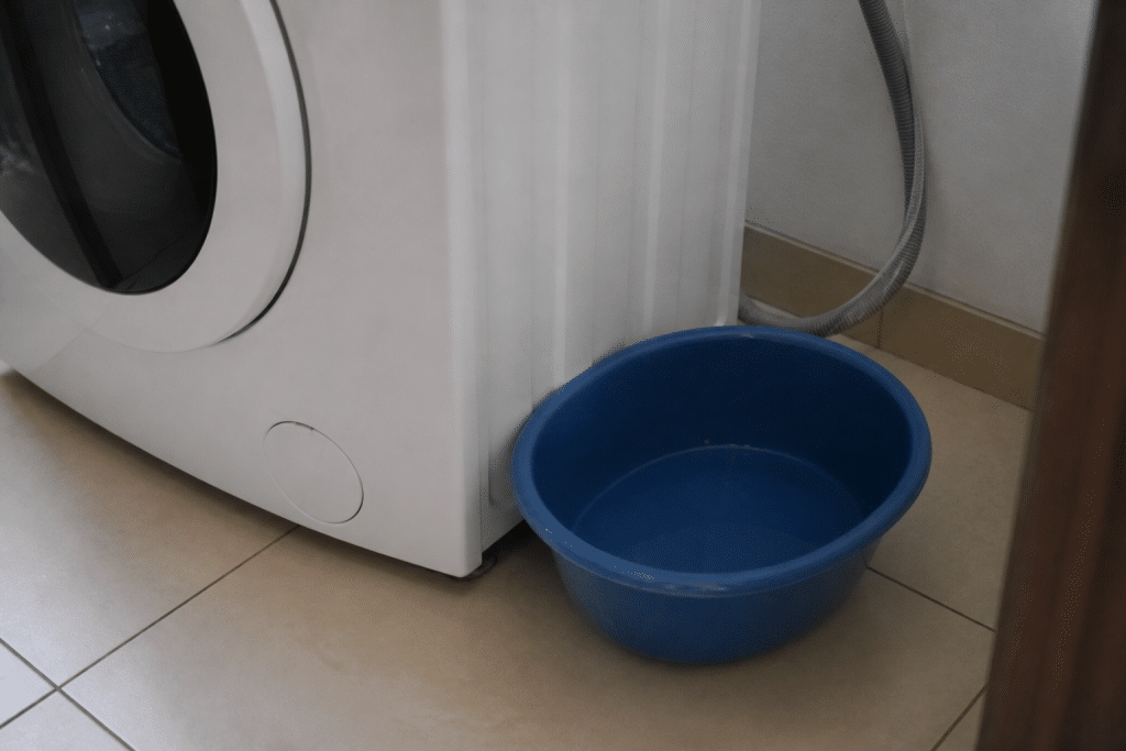 Lave-linge débranché avec bassine récupérant eau fuite