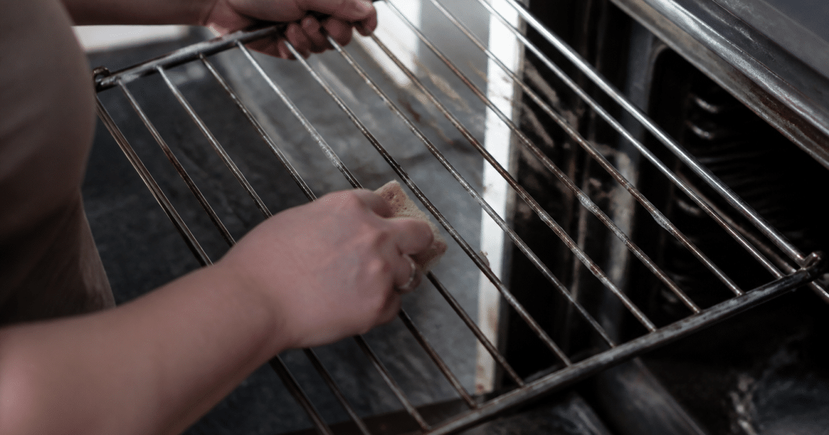 Main gantee frottant vigoureusement grille metallique four