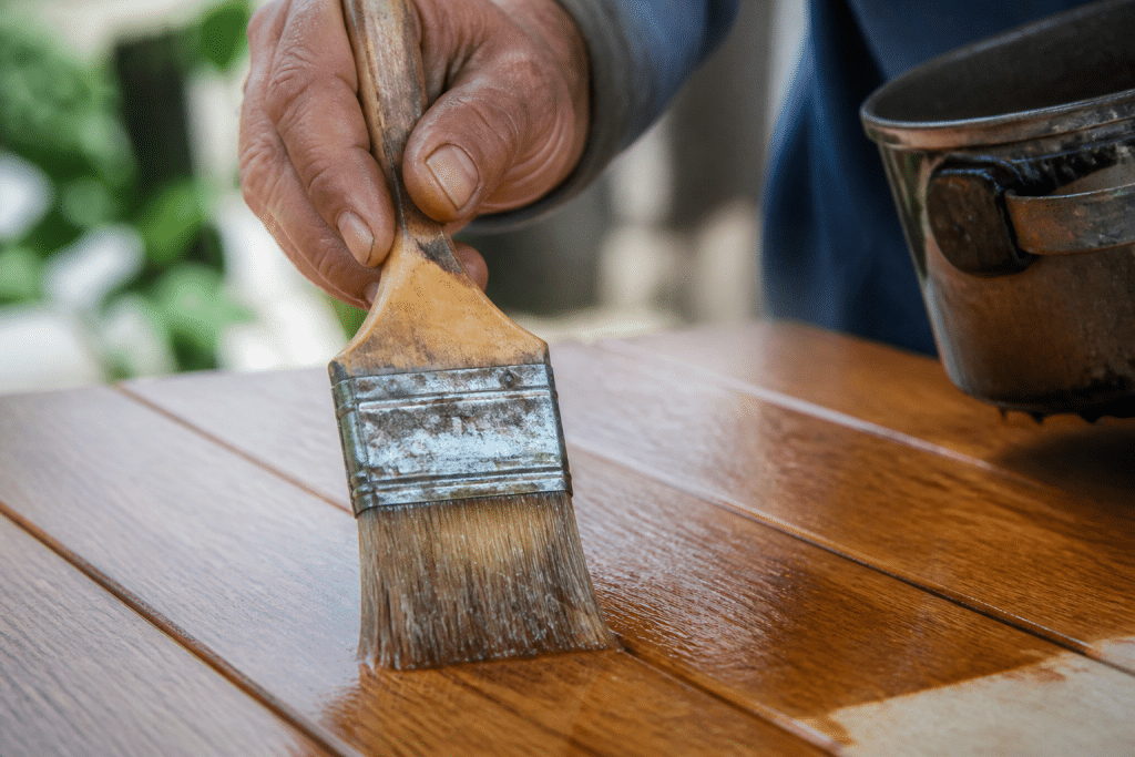 Pinceau appliquant lasure fine sur surface bois lisse