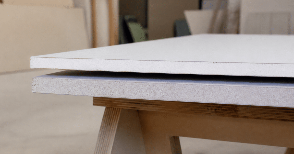 Deux plaques de plâtre empilées horizontalement, l'une blanche standard, l'autre grise hydromax