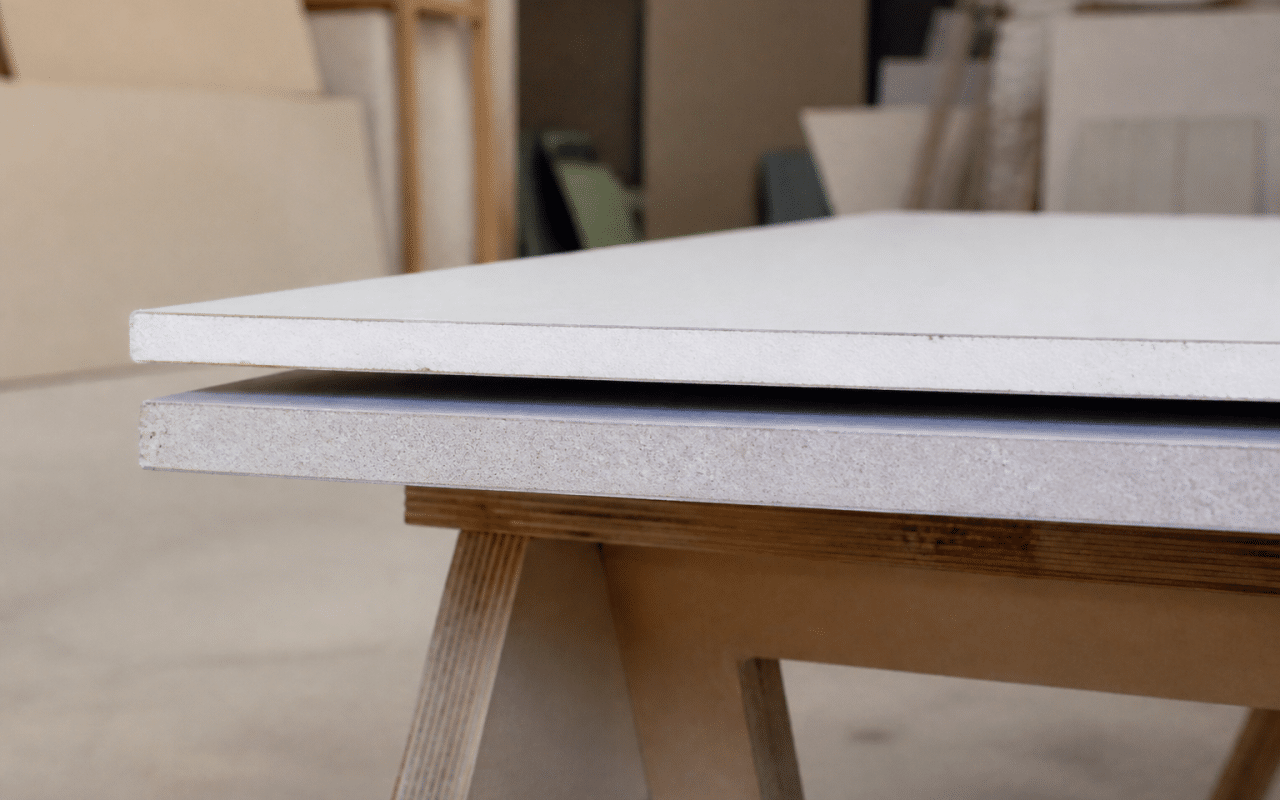 Deux plaques de plâtre empilées horizontalement, l'une blanche standard, l'autre grise hydromax