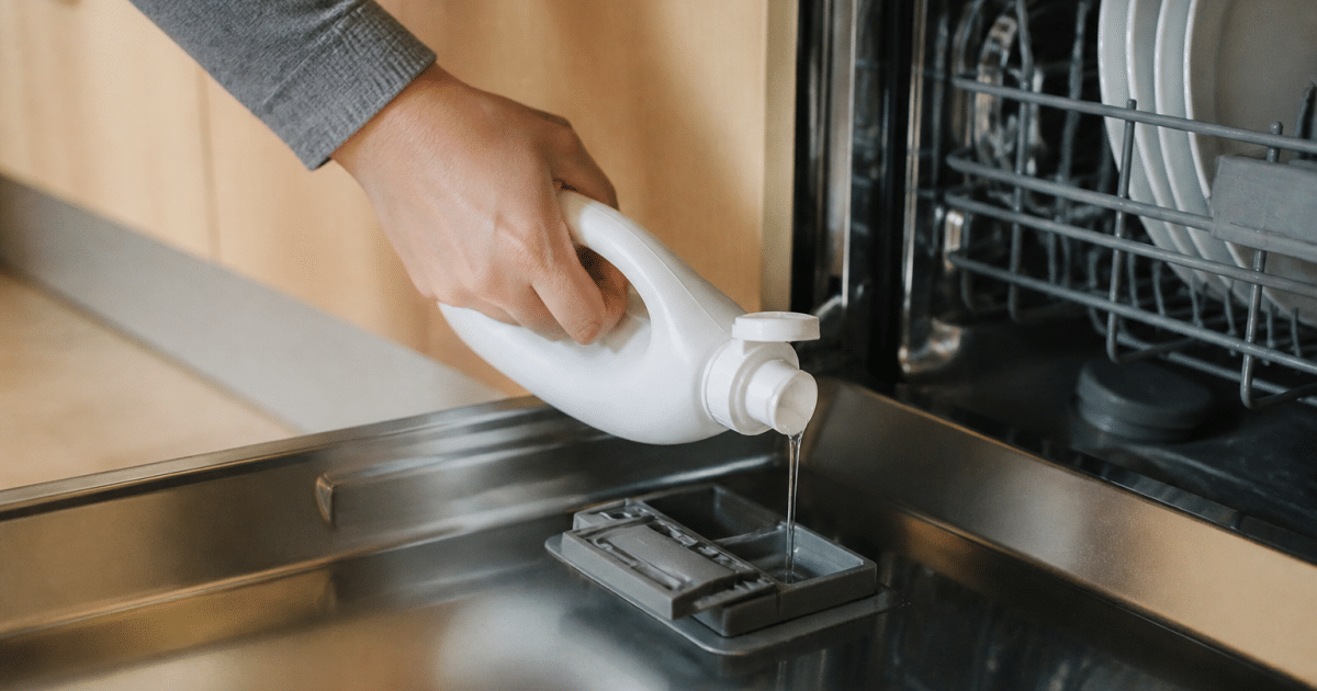 Main versant produit de rinçage dans compartiment lave-vaisselle