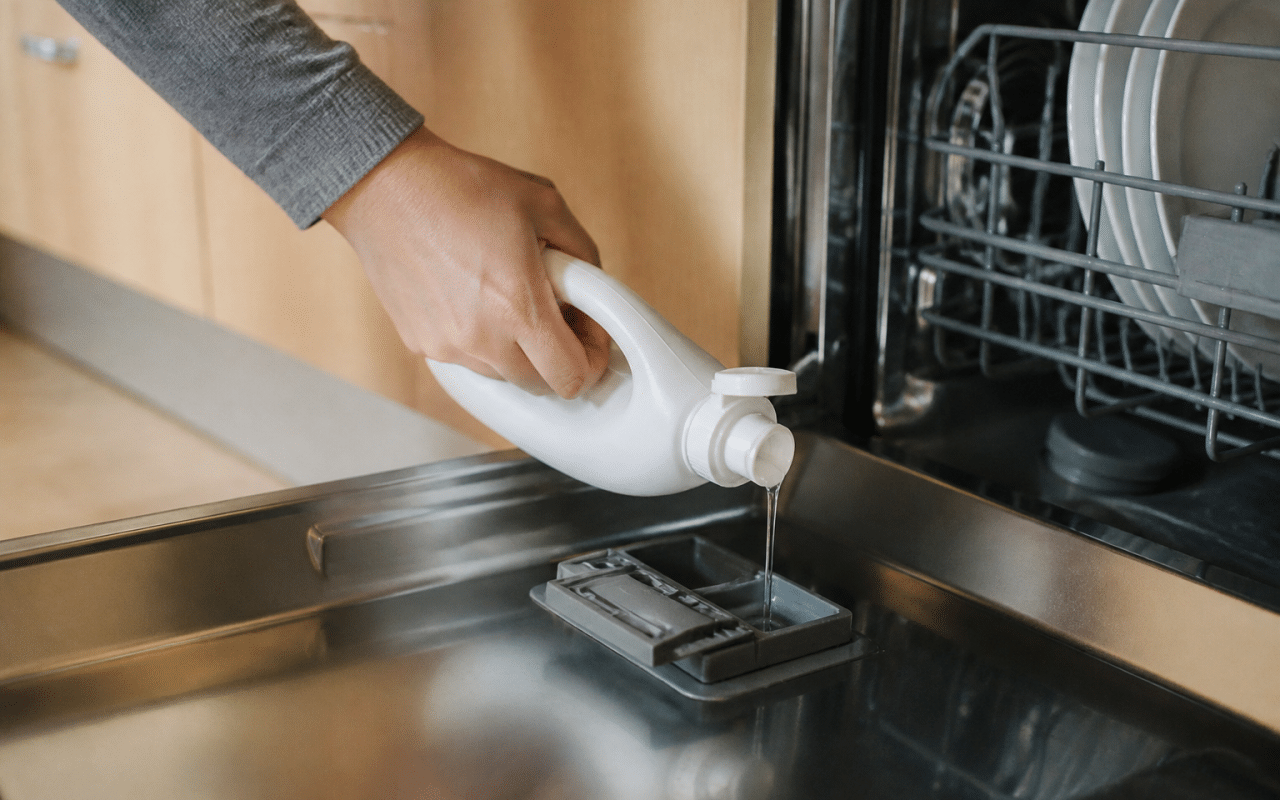 Main versant produit de rinçage dans compartiment lave-vaisselle