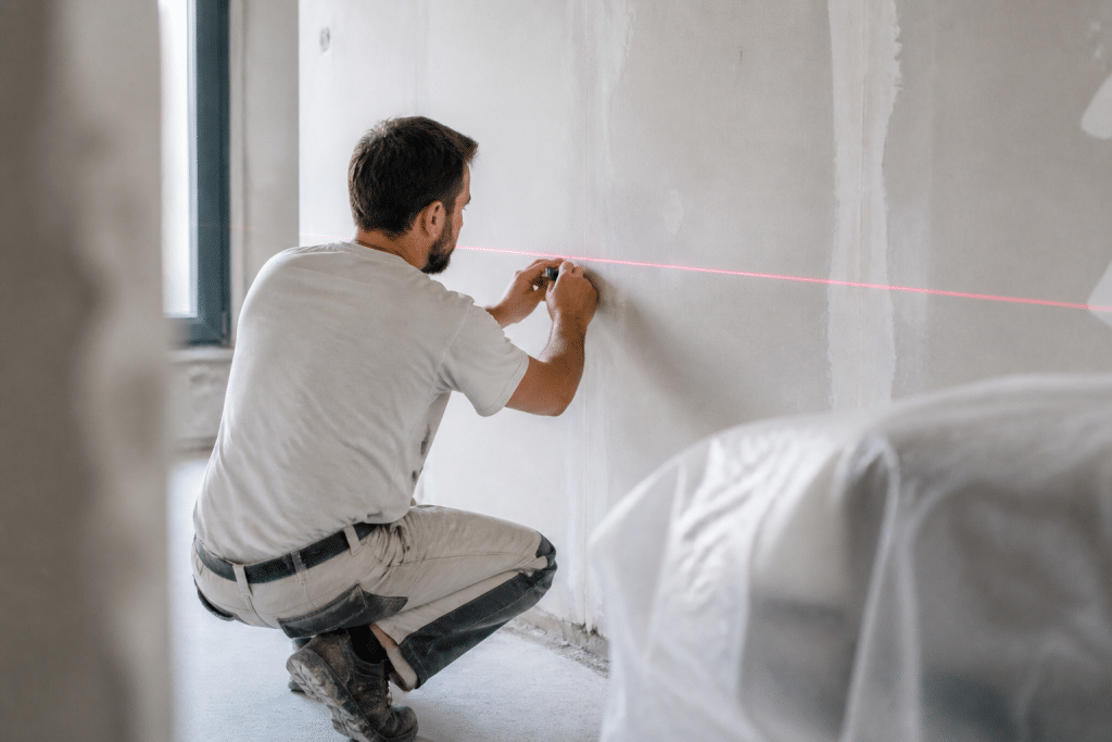 Ouvrier traçant lignes horizontales au laser sur mur