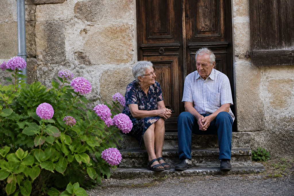 Maison ancienne avec couple agé assis sur porche